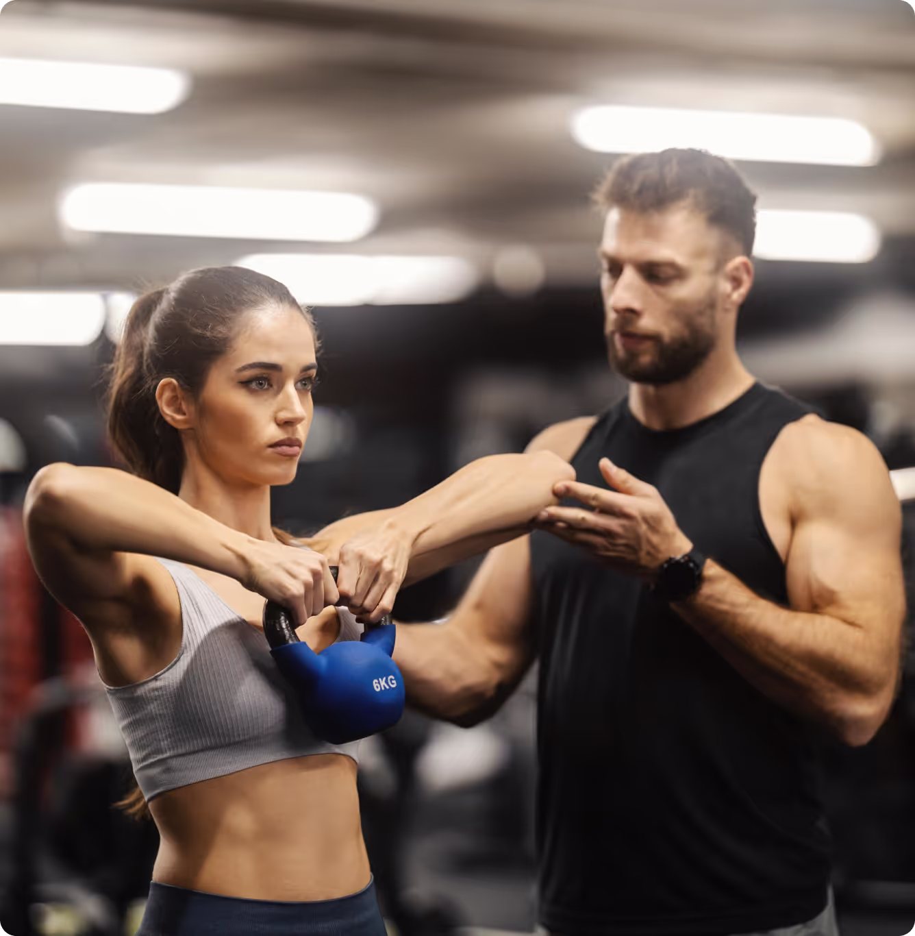 personal trainer helps a client do the workout with a dumbbell in the gym